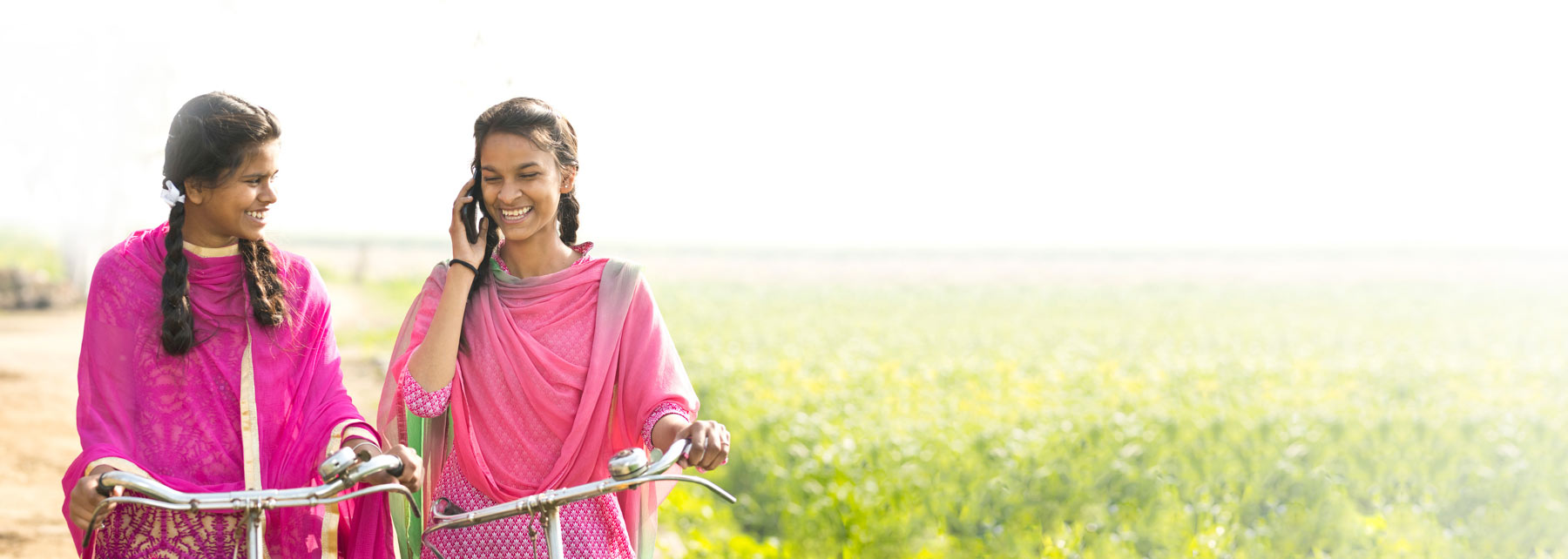 Two Indian Girls Talking on Bicycles