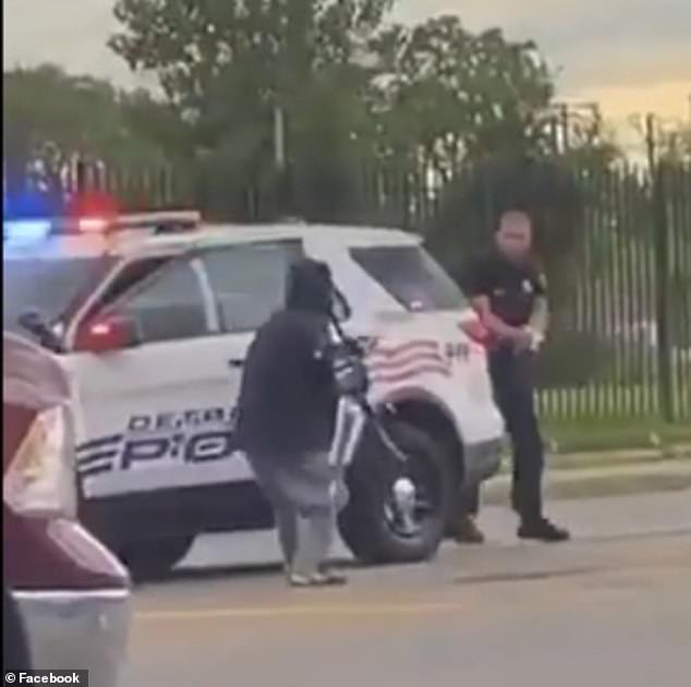 The officer on the right is seen taking cover behind the vehicle as the man armed with the sword and daggers approaches